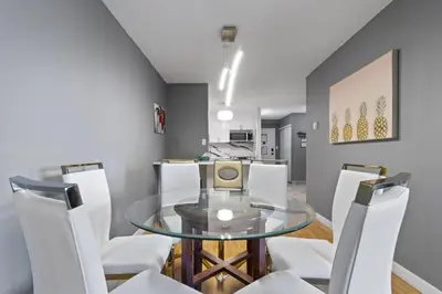 a dining room with a glass table and white chairs at Modern 2 bedroom next to Stampede, 17th w Parking in Calgary