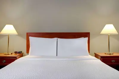 a bed with white sheets and two lamps on tables at Days Inn by Wyndham Whitecourt in Whitecourt
