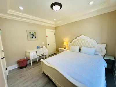 a bedroom with a large white bed and a desk at Vancouver Airport Love Home Inn in Richmond