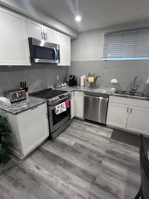 a kitchen with white cabinets and stainless steel appliances at Elegant Cozy Private Apartment in Calgary