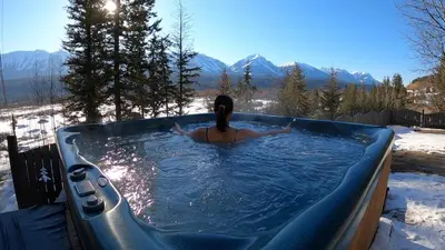 a woman in a hot tub in the snow at Alpenrose 100 King bed Hottub Mountains Views in Golden