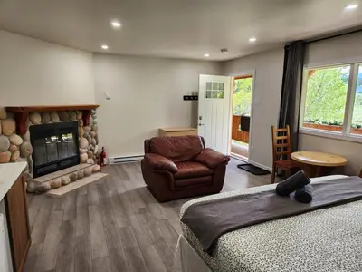 a bedroom with a couch and a chair and a fireplace at Alpenrose 100 King bed Hottub Mountains Views in Golden