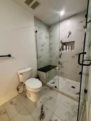 a bathroom with a toilet and a glass shower at Hilltop Vistas Kelowna in Kelowna