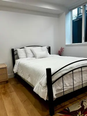 a bedroom with a bed with white sheets and a window at Hilltop Vistas Kelowna in Kelowna