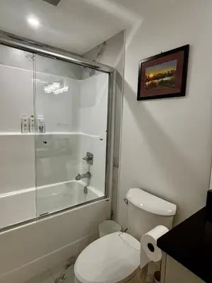 a bathroom with a toilet and a glass shower at Hilltop Vistas Kelowna in Kelowna