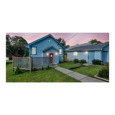 a blue house with a red door in a yard at Youbou Lakefront Getaway Relax And Unwind in Youbou