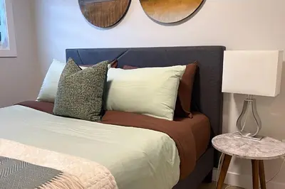 a bed with a blue headboard with pillows and a lamp at RomanticStylish|FreeWifi|KingBed|WEM|parking in Edmonton