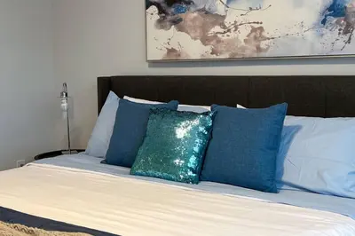 a bed with blue and white pillows on it at RomanticStylish|FreeWifi|KingBed|WEM|parking in Edmonton