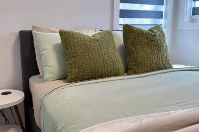 a bed with several pillows on it in a room at #RusticModern3CornerSuite|KingBED|Parking|WEM|wifi in Edmonton