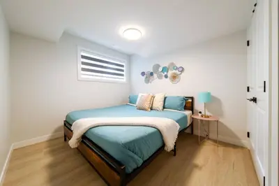 a bedroom with a bed with blue sheets and a window at •SteamyRomanticBsmntSuite•KingBed•Wifi•Netflix in Edmonton