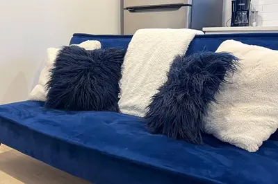 a blue couch with fluffy pillows on it at RoyalBlueBSMTsuite/KingBed/FreeParking/Netflix in Edmonton