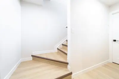 a staircase in a house with white walls and wooden floors at ~SweetTropicalBSMTsuite~KingBed|WIFI•parking in Edmonton