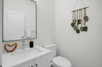 a bathroom with a sink and a toilet and a mirror at New Luxury Sleeps 7 AC Double Garage in Edmonton
