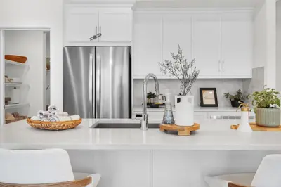 a kitchen with white cabinets and a stainless steel refrigerator at New Luxury Sleeps 7 AC Double Garage in Edmonton