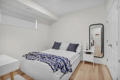 a white bedroom with a bed and a mirror at 1 BR Suite Stylish Coffee Station Stocked sleep 4 in Edmonton