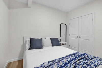 a white bedroom with a large bed with blue pillows at 1 BR Suite Stylish Coffee Station Stocked sleep 4 in Edmonton