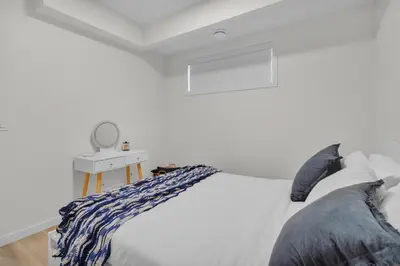 a white bedroom with a bed and a mirror at Trendy & Spacious Sleeps 9 AC Db Garage in Edmonton