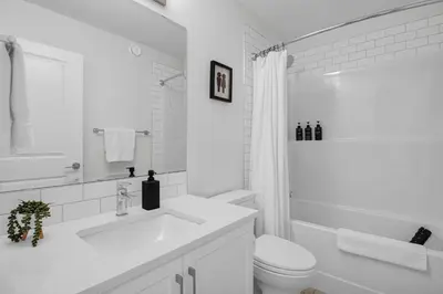 a white bathroom with a sink and a toilet at Trendy & Spacious Sleeps 9 AC Db Garage in Edmonton