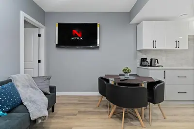 a living room with a couch and a table and a kitchen at Blissful Nest - Cozy, Classy 2 Bedroom Private Suite Netflix, free Parking, 20 minutes to West Edmonton Mall and Airport in Edmonton