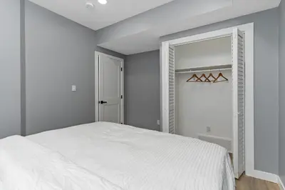 a white bedroom with a bed and a mirror at Blissful Nest - Cozy, Classy 2 Bedroom Private Suite Netflix, free Parking, 20 minutes to West Edmonton Mall and Airport in Edmonton