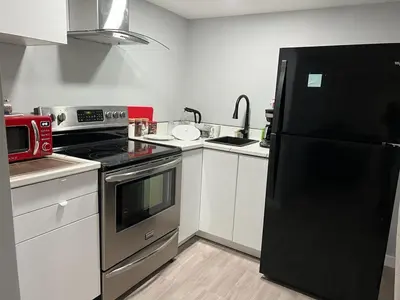 a kitchen with a black refrigerator and white cabinets at Gorgeous Basement Apartment in Calgary