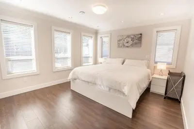a white bedroom with a large bed and windows at Upscale 4BR Vancouver in Vancouver