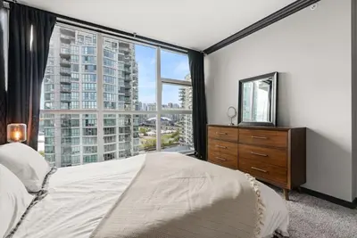 a bedroom with a bed and a large window at Large 1br Sub-Penthouse Near Science World in Vancouver