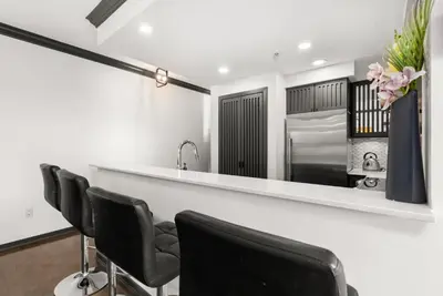 a kitchen with a bar with black chairs and a sink at Large 1br Sub-Penthouse Near Science World in Vancouver