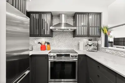 a kitchen with black cabinets and a stove top oven at Large 1br Sub-Penthouse Near Science World in Vancouver