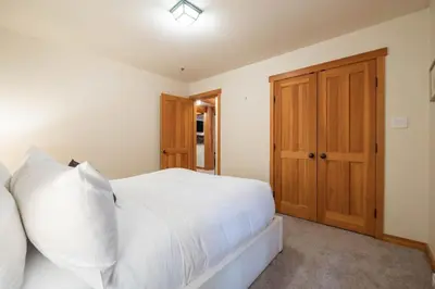 a bedroom with a white bed and a wooden door at Taluswood 14 by Outpost Whistler in Whistler