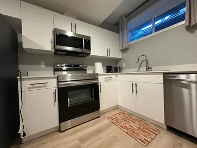 a kitchen with white cabinets and a sink and a microwave at Oisede in Edmonton