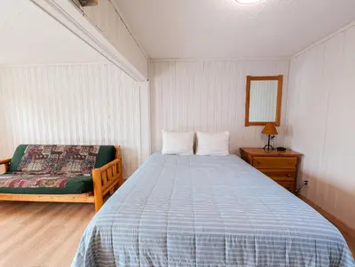 a bedroom with a bed and a chair and a mirror at Little Beach Resort in Ucluelet