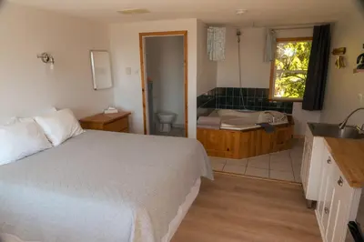 a bedroom with a bed and a bathroom with a sink at Little Beach Resort in Ucluelet