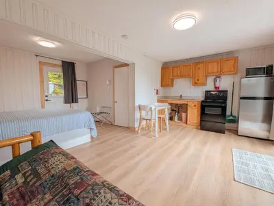 a room with a kitchen with a table and a refrigerator at Little Beach Resort in Ucluelet