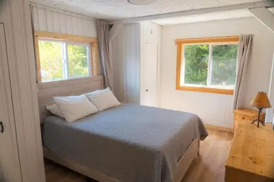 a bedroom with a bed and two windows at Little Beach Resort in Ucluelet