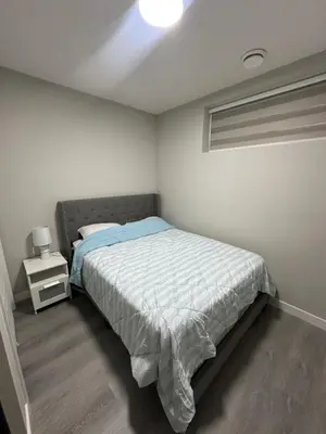a white bedroom with a bed and a night stand at Beautiful 2 bedroom 2 bath in NW Calgary in Calgary