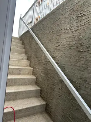 a staircase with a metal railing next to a stone wall at Beautiful 2 bedroom 2 bath in NW Calgary in Calgary