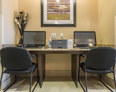 a desk with two computers and a printer and two chairs at Comfort Inn & Suites Edmonton International Airport in Nisku