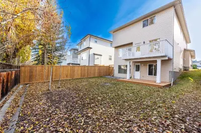 a white house with a fence in the yard at Valley Home 2 Bed 1 Bath Walkout Basement Apartment, 1hr to Banff, 40 Mins Canmore, 5 mins to WinSport & Olympic park in Calgary