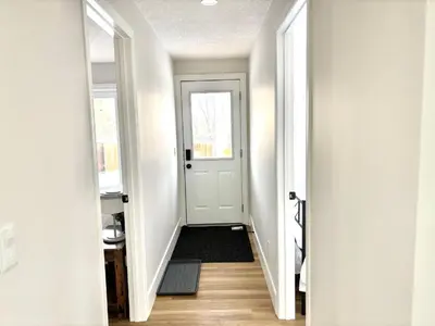 a hallway with a white door and a black rug at Valley Home 2 Bed 1 Bath Walkout Basement Apartment, 1hr to Banff, 40 Mins Canmore, 5 mins to WinSport & Olympic park in Calgary