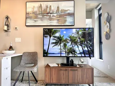 a living room with a large screen tv on a wall at MicroNest - Modern Overlooking Downtown Parking in Calgary