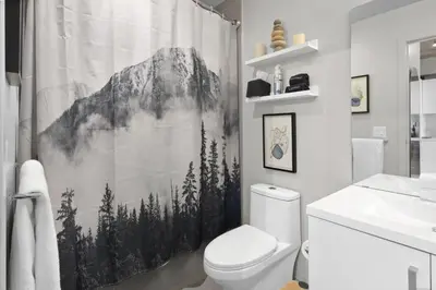 a bathroom with a mountain shower curtain with a toilet at MicroNest - Modern Overlooking Downtown Parking in Calgary