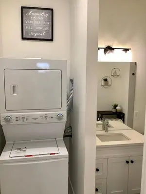 a white bathroom with a sink and a mirror at Sapphire Lux Queen Suite in Kamloops