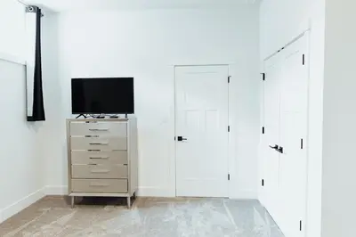 a bedroom with white walls and a tv and two closets at Sapphire Lux Queen Suite in Kamloops