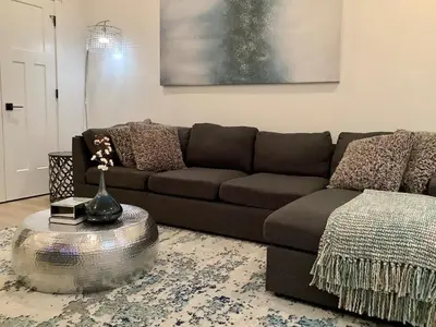 a living room with a brown couch and a table at Sapphire Lux Queen Suite in Kamloops