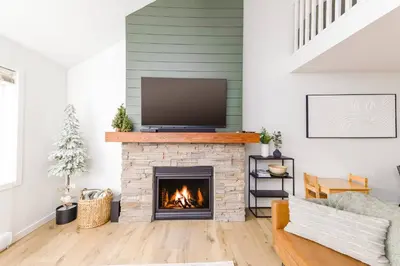 a living room with a fireplace with a flat screen tv at Wintergreen Retreat w/Hot Tub by Village in Kelowna