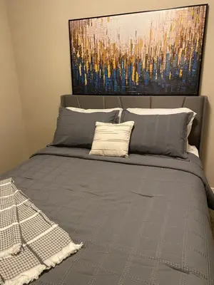 a bedroom with a bed with a painting on the wall at Mahogany's Comfy Haven in Calgary