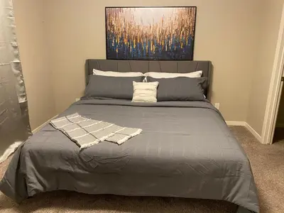 a bedroom with a bed with a painting on the wall at Mahogany's Comfy Haven in Calgary