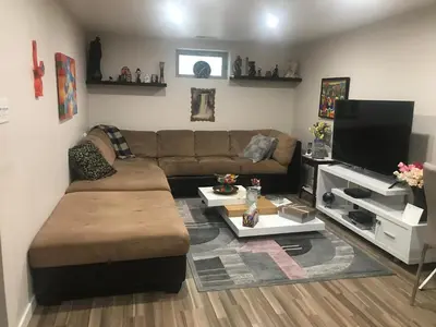 a living room with a couch and a flat screen tv at Dolly's Deluxe Suite in Fort Saskatchewan