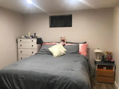 a bedroom with a bed with a teddy bear sitting on it at Dolly's Deluxe Suite in Fort Saskatchewan